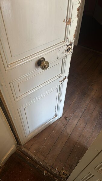 Porte intérieure ancienne avec cylindre retiré, boiserie éclatée, réparation de serrure en cours
