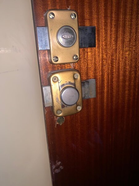 deux verrous de surface sur porte en bois, boîtier inférieur endommagé et bois éclaté